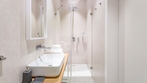 Een moderne badkamer met een grote wastafel, een spiegel en een douchecabine.