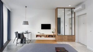 Een moderne slaapkamer met een bed, een bureau, een stoel, een televisie en een kledingkast.