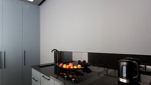 Een moderne keuken met een zwart aanrecht, een waterkoker en een schaal met fruit.