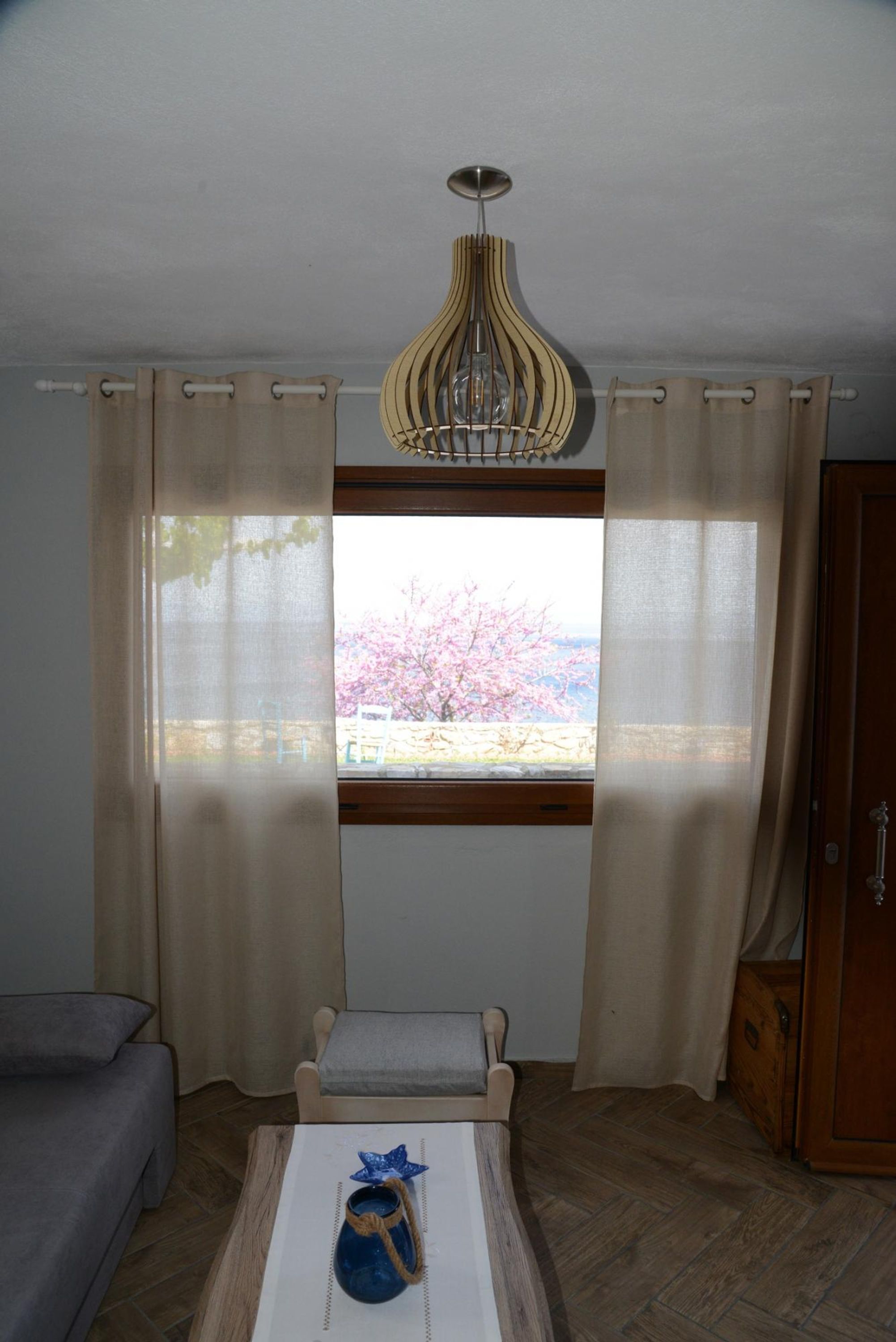 Ein Zimmer mit Fenster, einem Sessel, einem Tisch und einem Holzschrank.