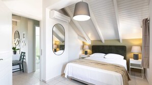 Une chambre à coucher avec un grand lit, deux tables de chevet avec des lampes, un miroir et un ventilateur de plafond.