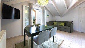 Una sala de estar moderna con comedor, un sofá y un televisor montado en la pared.
