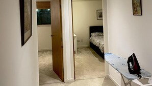 Une chambre à coucher avec un lit, un petit bureau et une planche à repasser.