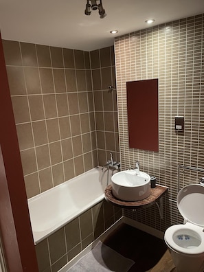 Een moderne badkamer met een bad, een wastafel en een toilet.