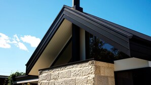 A building with a stone base, a black chimney, and a sloped roof. - Maple Suite, Berry - by Linnaeus Collection (Berry)