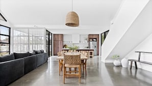A modern kitchen with a dining area, large windows, and a staircase. - Maple Suite, Berry - by Linnaeus Collection (Berry)