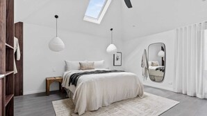 A bedroom with a bed, bedside tables, a mirror, and a skylight. - Maple Suite, Berry - by Linnaeus Collection (Berry)