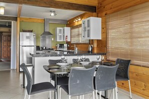 Cocina moderna con una isla central, electrodomésticos de acero inoxidable y una zona de comedor con sillas y una mesa preparada para cuatro.