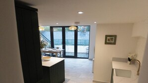 A modern kitchen with a central island, a built-in oven, and a sink with a gold faucet. - Cosy Central Townhouse in Woodstock (Woodstock)