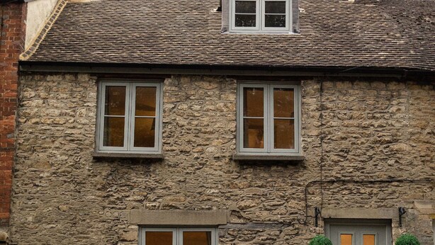 A stone building with a grey door, two windows, and a small dormer window. - Cosy Central Townhouse in Woodstock (Woodstock)