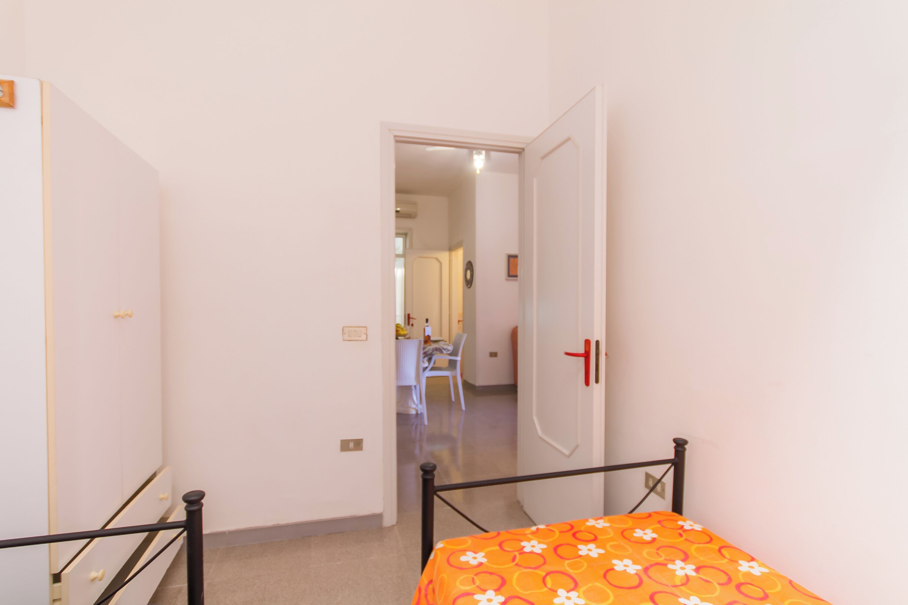 A bedroom with a bed, a wardrobe, and a door leading to another room.