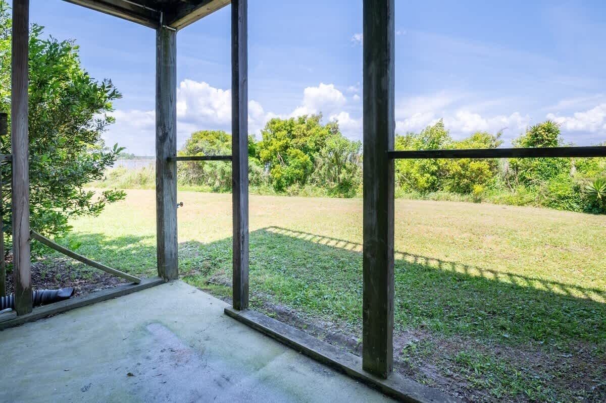 Un espace extérieur abrité, doté d’un sol en béton, de rampes en métal et offrant une vue sur un champ verdoyant et des arbres.