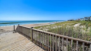 A wooden boardwalk leading to a beach with clear skies. - Jolly Roger (North Topsail Beach)