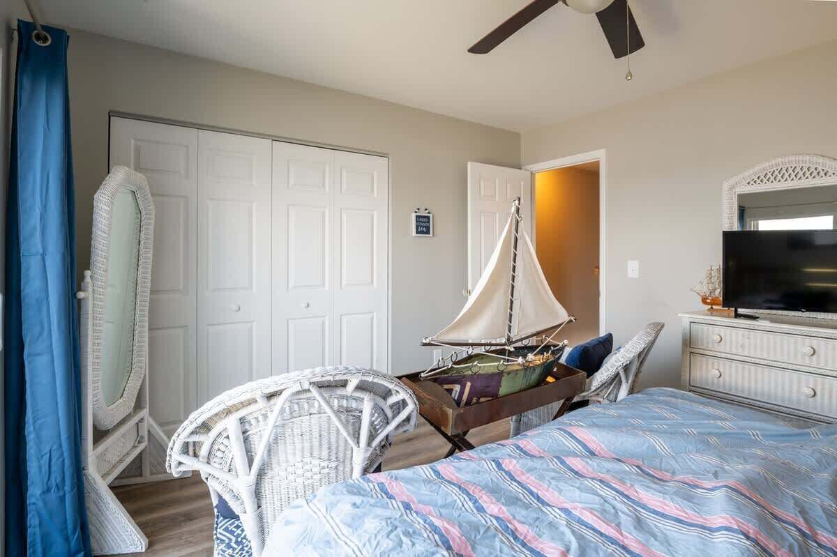 A bedroom with a bed, a television, a sailboat model, and a wardrobe.