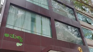 A modern building with a glass facade, a green sign reading "ATHULYA Stays," and a staircase leading to the entrance. - Athulya Stays (Bengaluru)