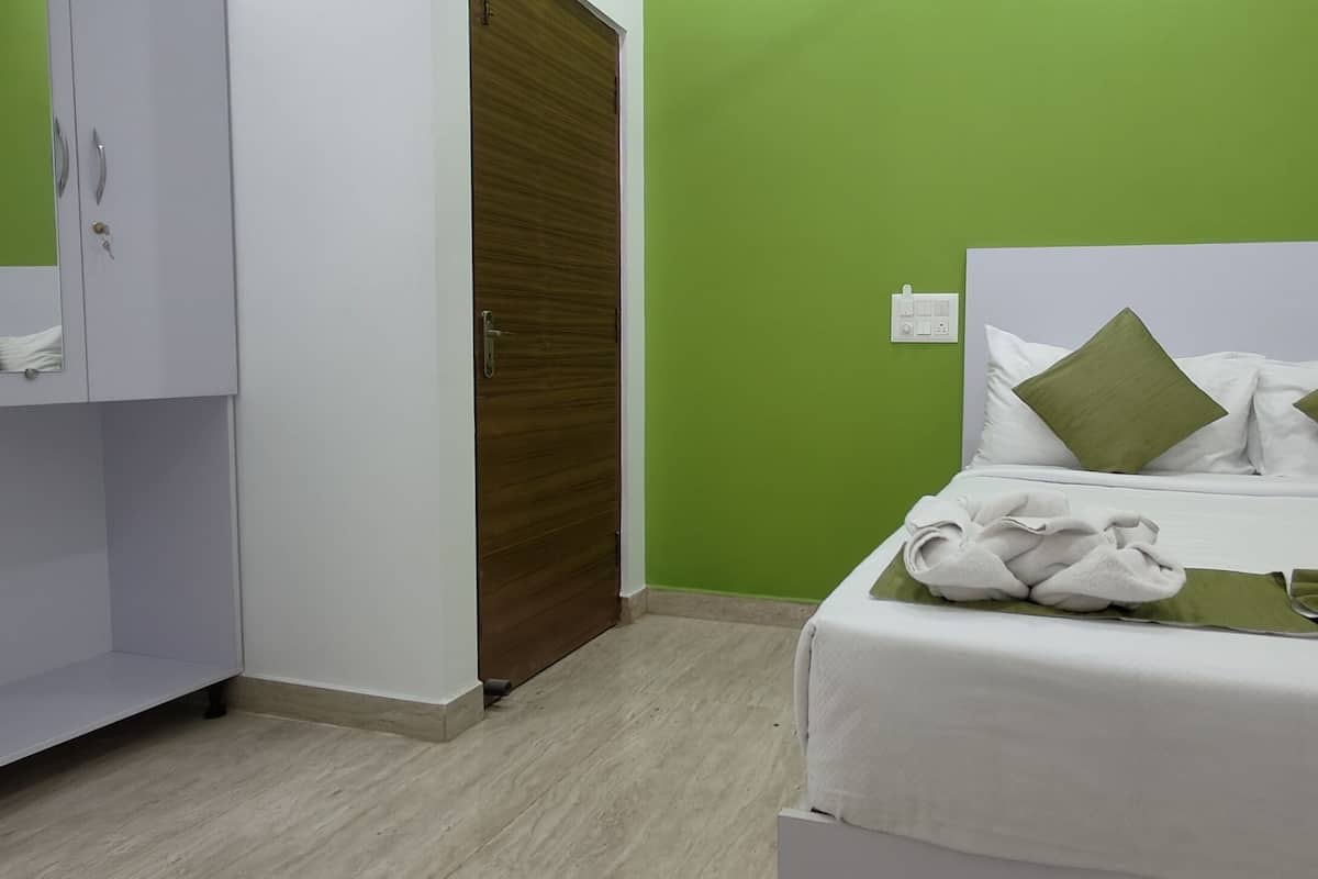 Habitación de hotel con cama, paredes verdes, un armario y una toalla verde sobre la cama.