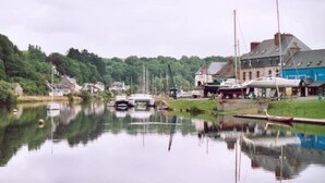 A calm harbor with boats docked, a small pier, and buildings along the water's edge.