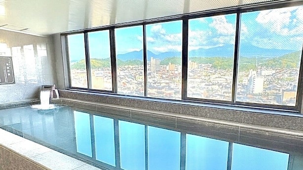 A long, empty swimming pool with a cityscape view through large windows. - Yonago Universal Hotel  (Yonago)