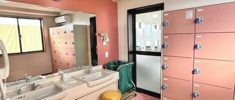 A hotel bathroom with a sink, mirror, and storage lockers.