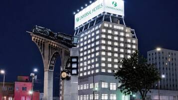 A hotel with a prominent sign for Universal Hotels, featuring a clock and a large illuminated sign.