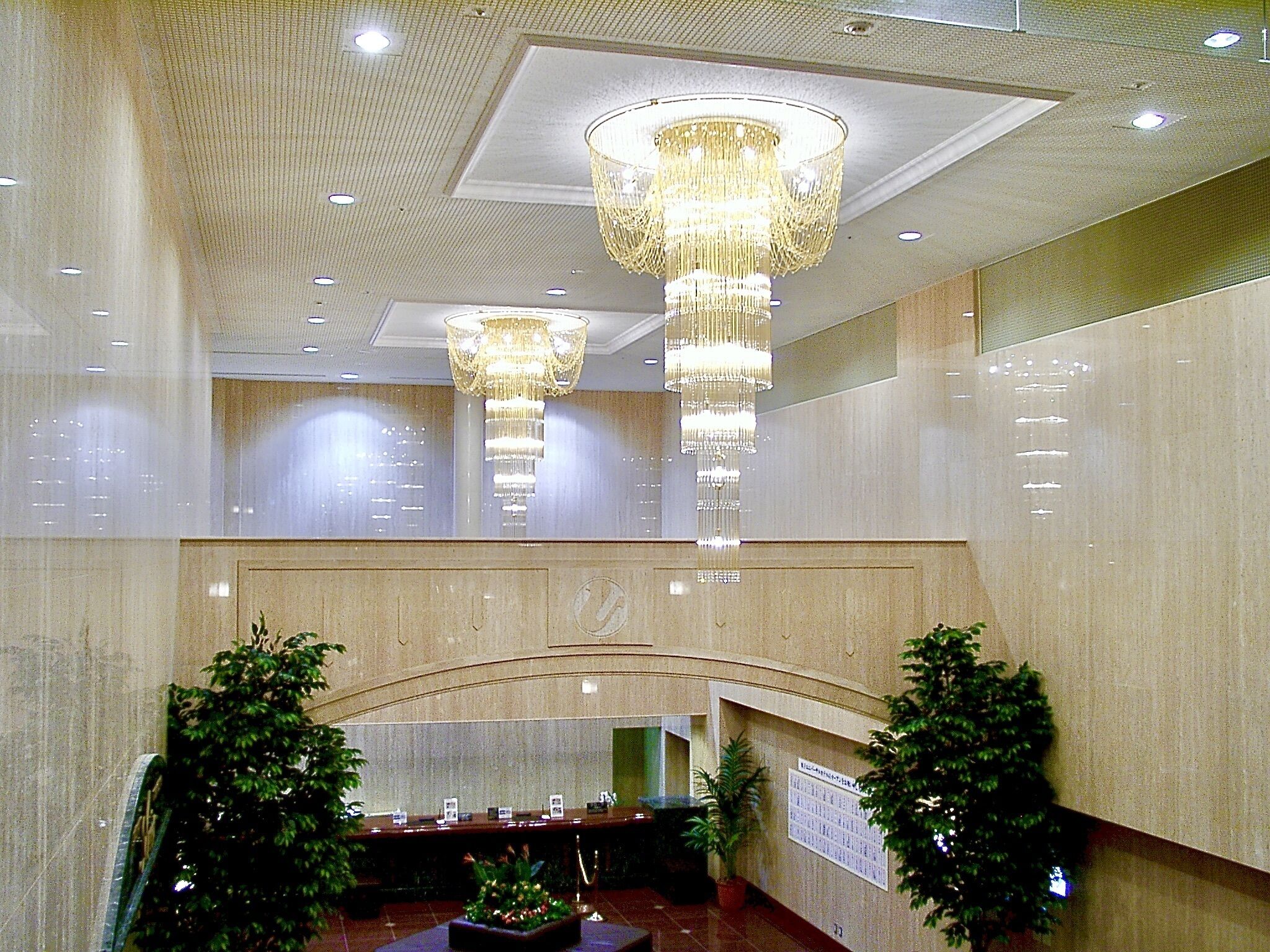 A spacious lobby with high ceilings, multiple chandeliers, and a reception desk.