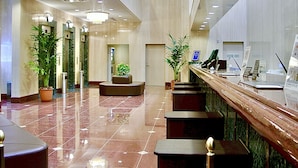 A spacious lobby with a reception desk, seating areas, and potted plants. - Yonago Universal Hotel  (Yonago)