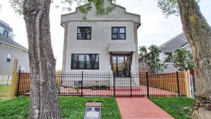 A two-story building with a flat roof, a front entrance with a door, and a black metal fence. - Dt 1Bed 1bath Cozy Suite 8 Min Walk To Arena (Edmonton)