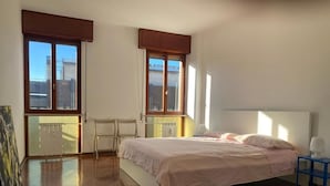 A bedroom with a bed, a desk, and a chair. There are two windows with blinds. - Ca' Beuys in the Kitchen Apartment (Venezia)
