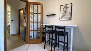 A hallway with a white door, a white table with black chairs, and a framed picture on the wall. - Ca' Beuys in the Kitchen Apartment (Venezia)