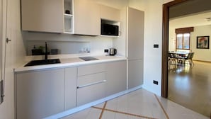 A modern kitchen with white cabinets, a microwave, and a coffee maker. - Ca' Beuys in the Kitchen Apartment (Venezia)