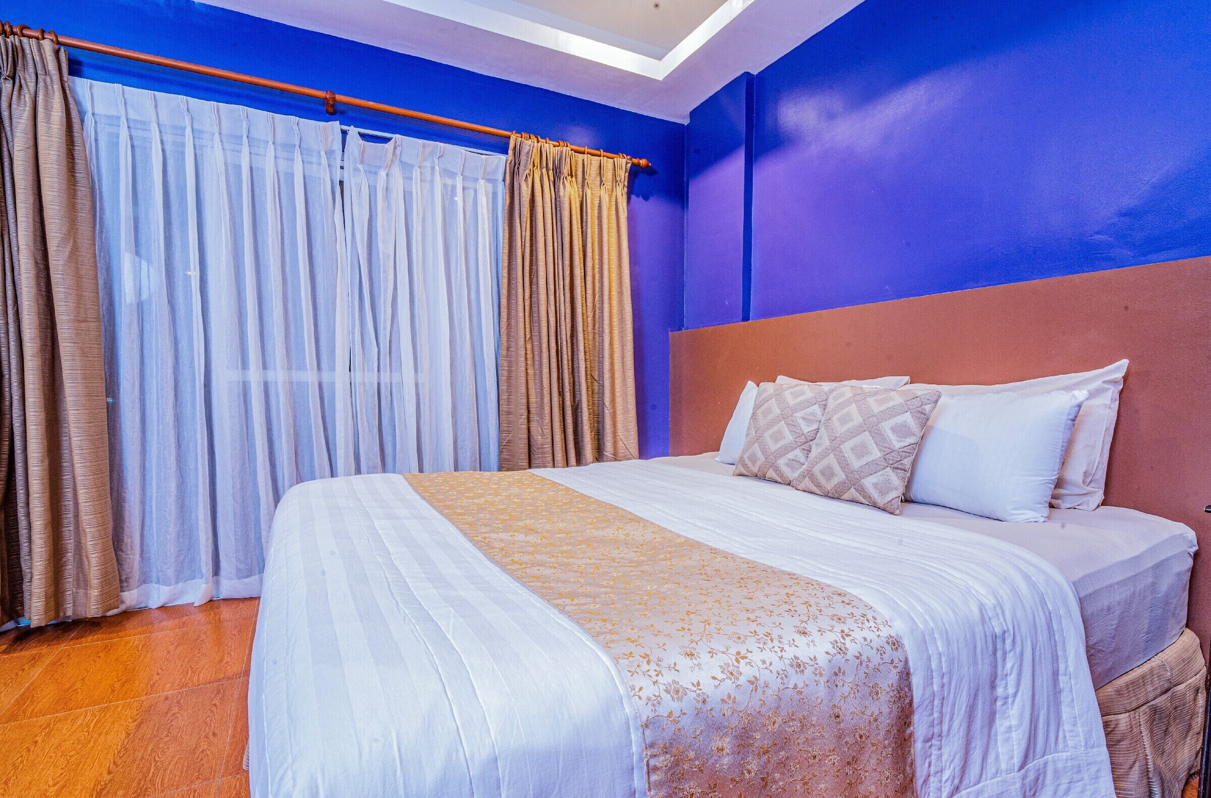 A bedroom with a large bed, a headboard, and curtains.