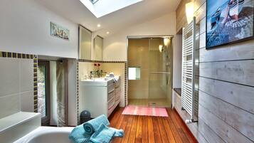 Een moderne badkamer met dakraam, ligbad, douche en een houten vloer.