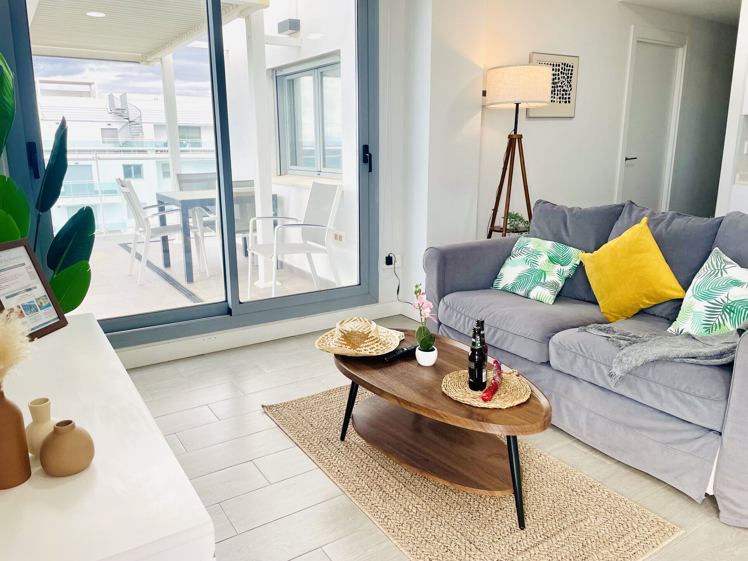 Una sala de estar moderna con un sofá gris, una mesa de centro de madera y vistas al balcón exterior.