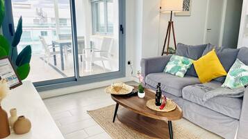 Una sala de estar moderna con un sofá gris, una mesa de centro de madera y vistas al balcón exterior.