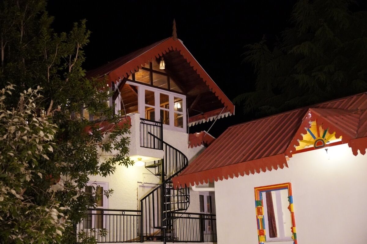 Un bâtiment à deux étages doté d’un escalier en colimaçon, d’un balcon et d’une petite fenêtre ornée de motifs colorés.