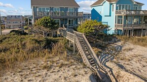 A beachfront property with a wooden boardwalk leading to a building with multiple balconies. - A Southern Charm - 5BR Oceanfront House in Surf City Sleeps 12 (Surf City)