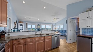 A spacious kitchen with wooden cabinets, a granite countertop, and a built-in dishwasher. - A Southern Charm - 5BR Oceanfront House in Surf City Sleeps 12 (Surf City)