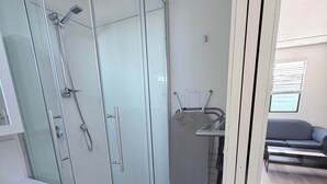 A modern bathroom with a glass shower enclosure, a white sink, and a compact storage unit. - Private Studio | Convenient Stay Near Hobart (Claremont)
