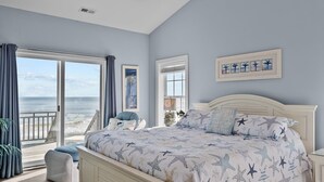 Un dormitorio con una cama grande, vistas al océano y un balcón.