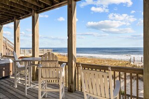 A wooden deck with two Adirondack chairs and a grill, overlooking a beach with a wooden walkway and ocean view. - 'Sea Dawg (North Topsail Beach)