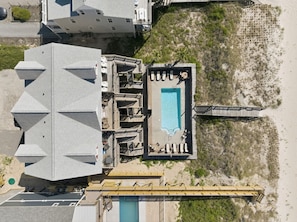 An aerial view of a hotel with a swimming pool, a deck area, and a beach access.