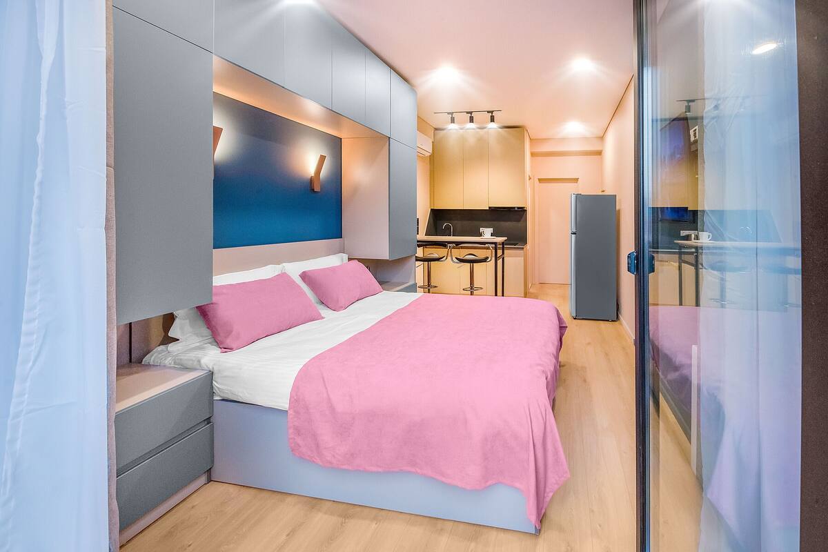 A modern bedroom with a bed, bedside tables, and a glass partition.
