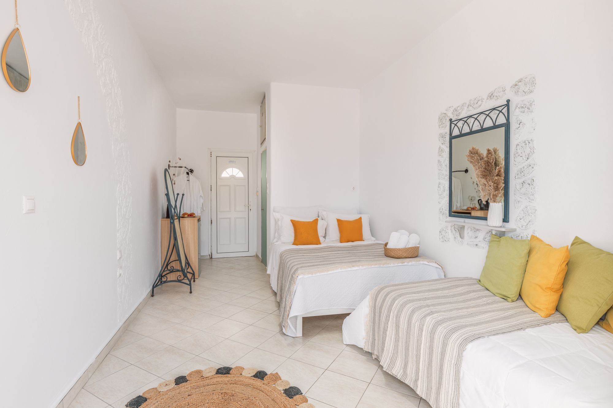 A bedroom with two beds, a mirror, a door, and a small rug.