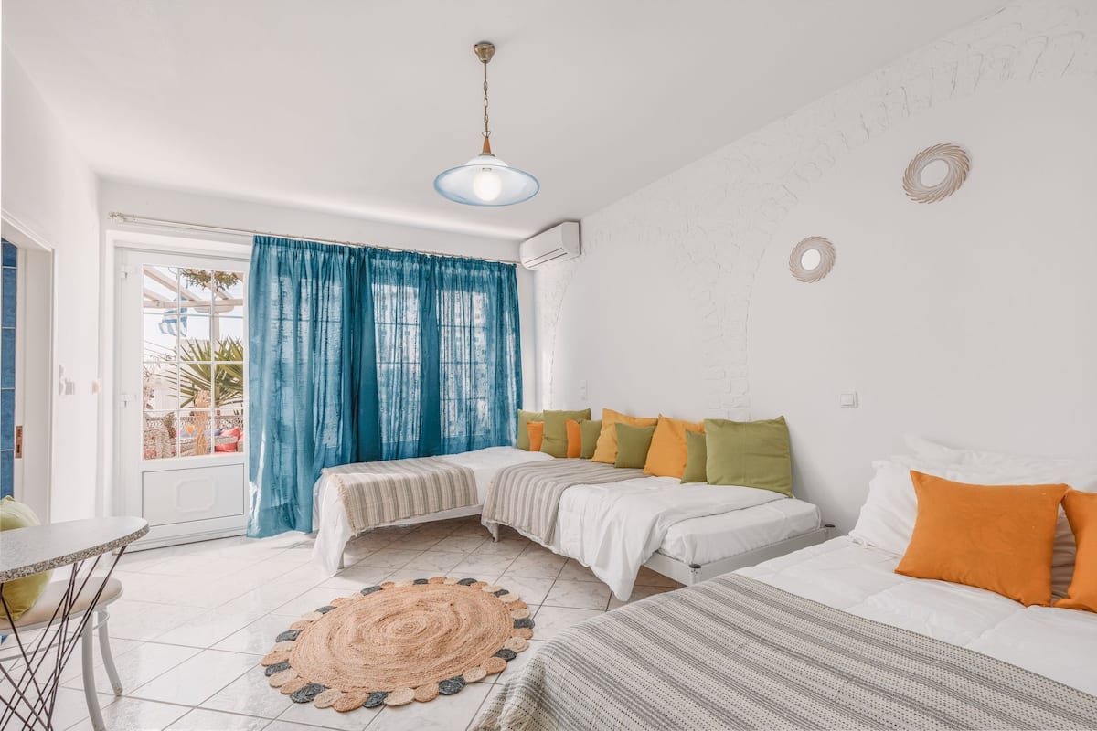 Une chambre à coucher avec un lit, une table et une chaise. Il y a une fenêtre avec des rideaux.