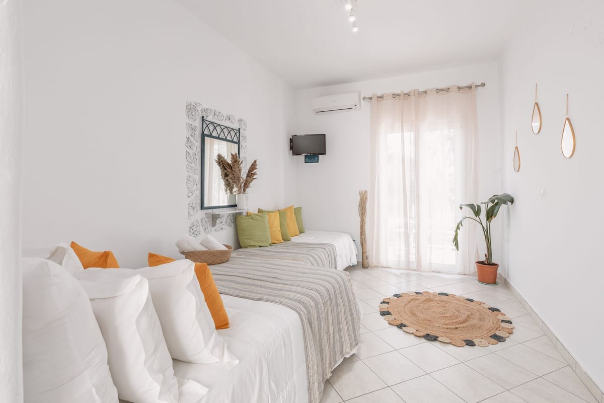 Une chambre à coucher moderne avec un lit, un canapé, une télévision et une plante en pot.