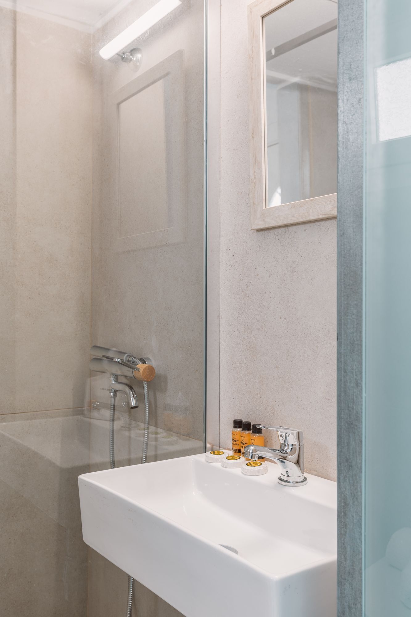 Un baño moderno con un lavamanos blanco, dos grifos y una cabina de ducha de vidrio.