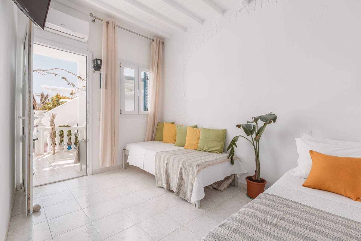 Une chambre avec un lit, une plante en pot et une vue sur le balcon extérieur.