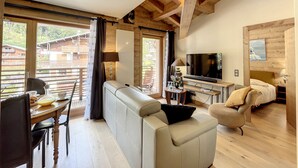 Una sala de estar acogedora con un sofá, televisor y comedor con mesa y sillas.