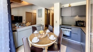 Una cocina moderna con microondas, horno y comedor con una mesa redonda y sillas.