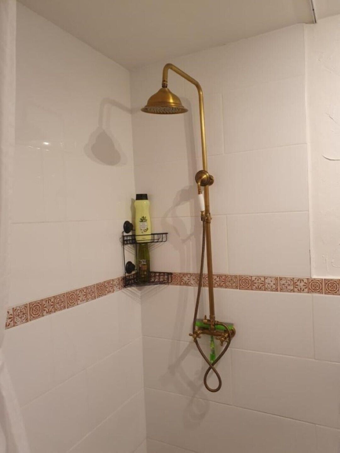 A shower with a gold showerhead and a green handheld showerhead.